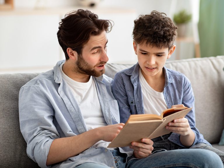 A father and son read a book together.