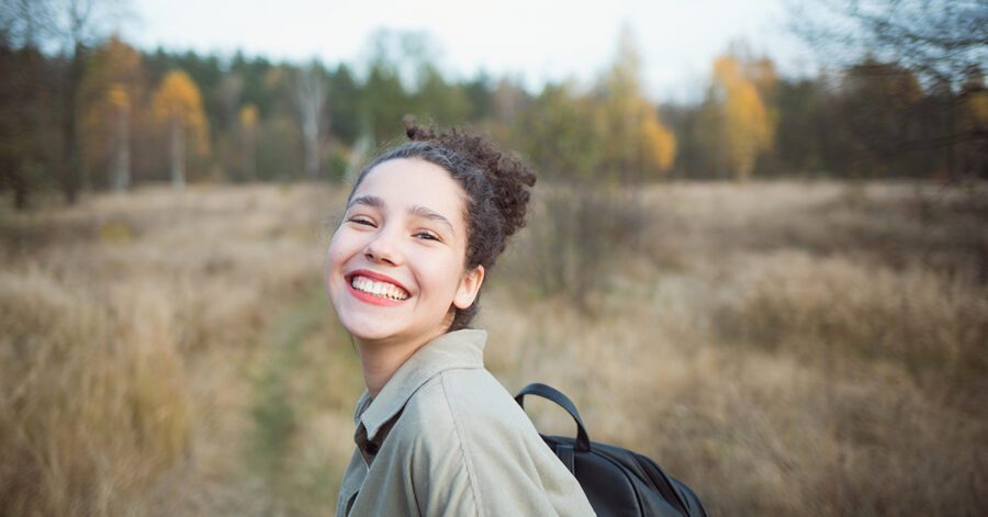 portrait of young pretty mixed race teen girl outdoor in autumn. happy woman with finely curly hair in field of reed grass.