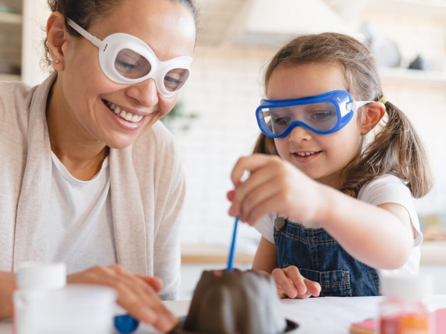 Mother and daughter in protective glasses watching a chemistry experiment together