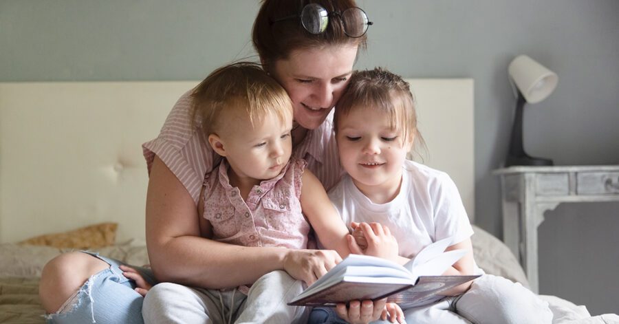 A mother reading aloud to two young toddlers/lifelong learners.