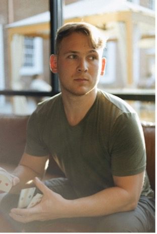 Man with green shirt sitting and holding playing cards
