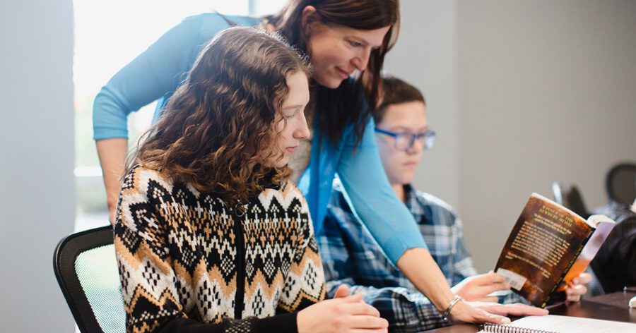 A homeschooling tutor engages students in thoughtful literature discussion, fostering curiosity and critical thinking through the classical education method