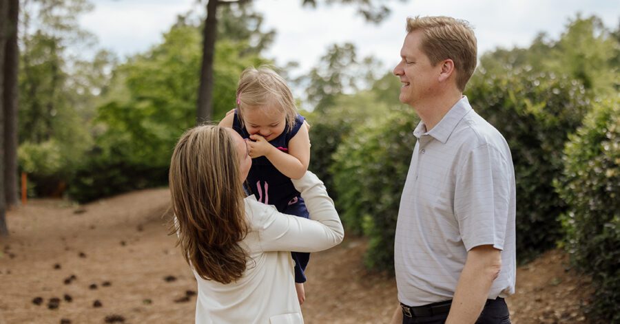 A mother holding her daughter who has special needs while dad looks on.