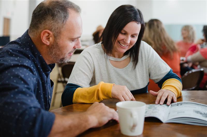 two homeschool parents working through a notebook at a Parent Practicum event